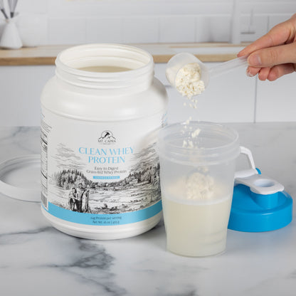 Person pouring whey protein into a shaker cup