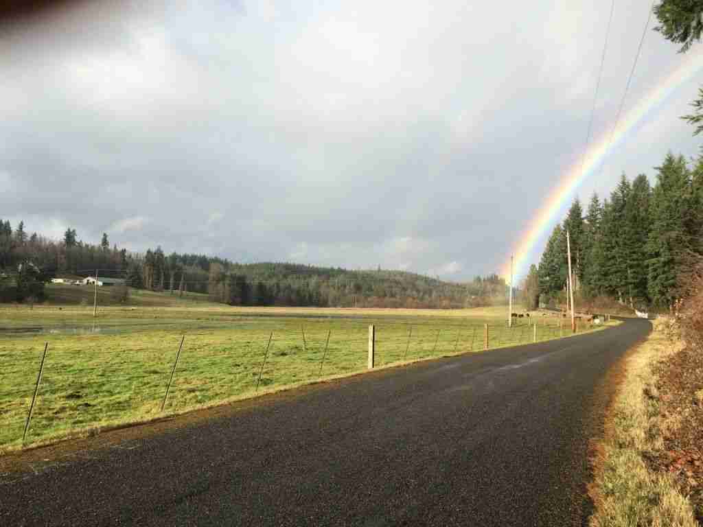 Rainbow crosses the road at the foot of the Mt. Capra farm